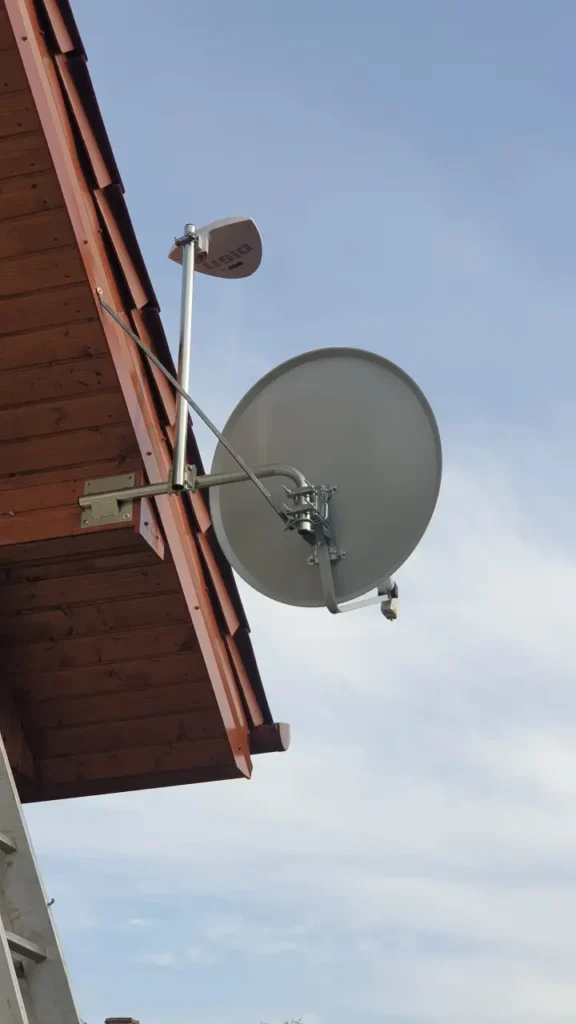 Jasna antena satelitarna na poddaszu. W tle błękitno-białe niebo