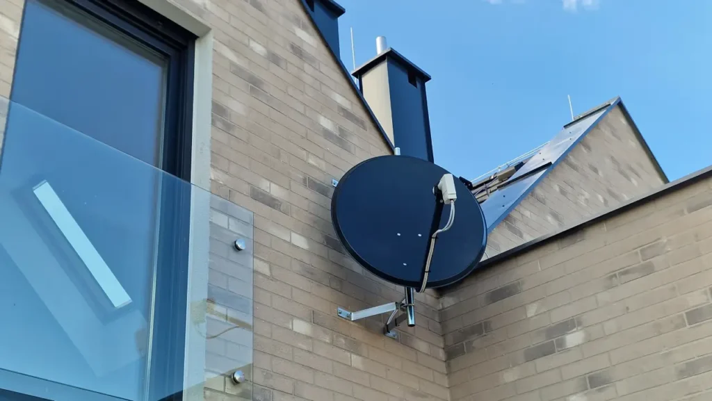 Czarna antena satelitarna na elewacji z cegły w odcieniach jasnych