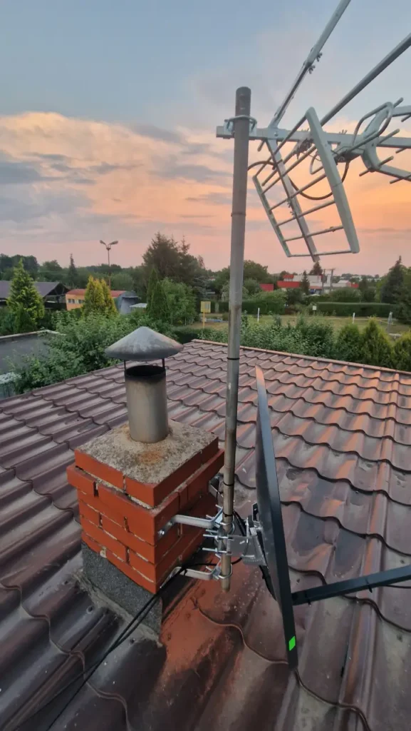 Antena kierunkowa DVB-T2 na kominie w tle dachy domków jednorodzinnych